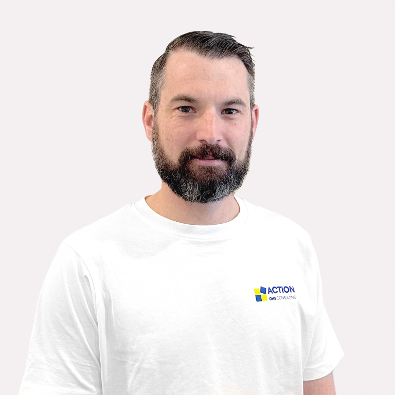 A man with short dark hair and a beard, wearing a white t-shirt with a blue and yellow "ACTION GPS CONSULTING" logo, stands against a plain light background.