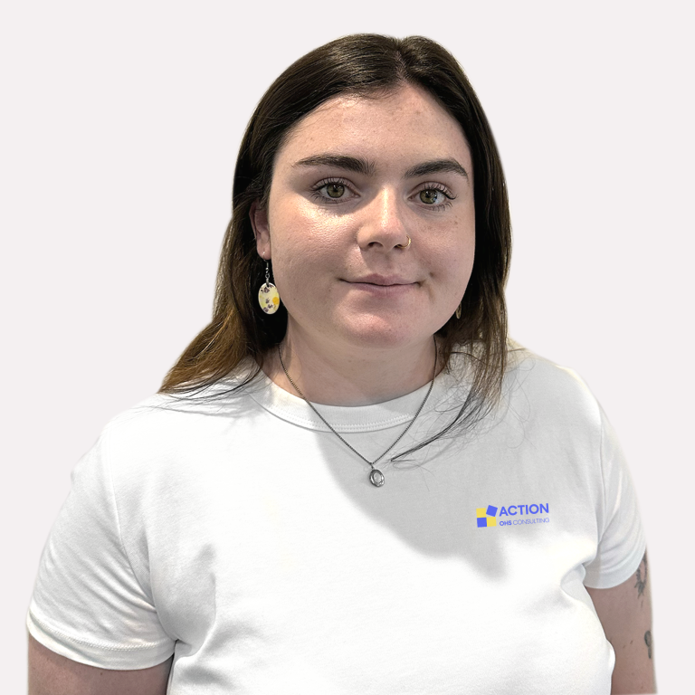 A woman with straight brown hair wearing a white t-shirt with an "ACTION ONE CONSULTING" logo, a necklace, and patterned earrings, standing against a plain light background.