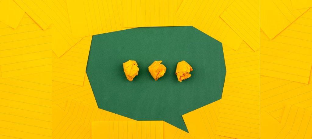 A green speech bubble shape is surrounded by overlapping yellow lined papers. Inside the speech bubble are three crumpled yellow paper balls lined up horizontally.